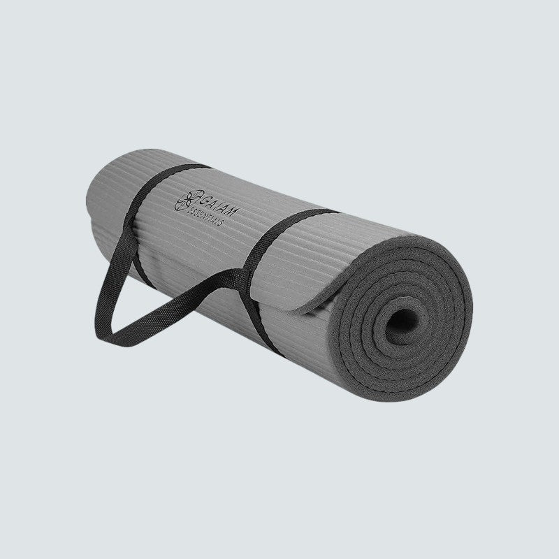 Gray yoga mat with a black carrying strap on a light gray background