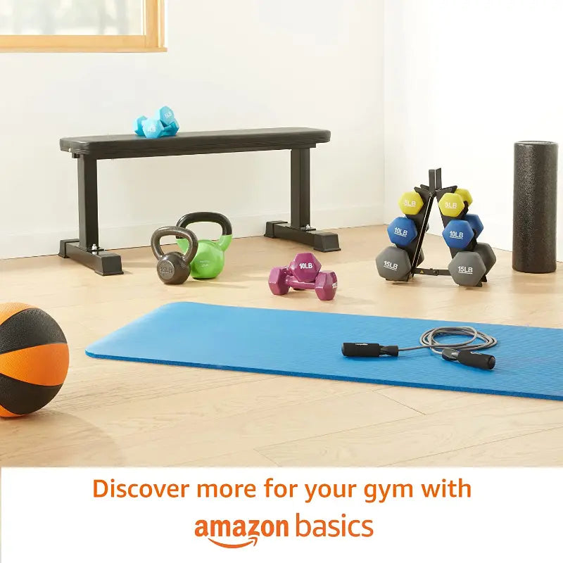Gym equipment including a bench, kettlebells, dumbbells, and a mat on a wooden floor with 'Amazon Basics' text.