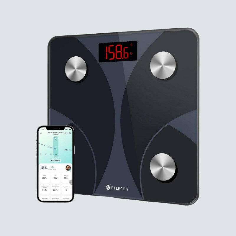 Black digital body fat scale with smartphone displaying app on light gray background