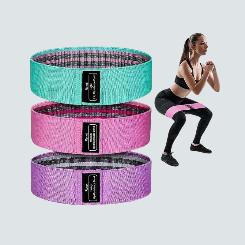 Stack of resistance bands in green, pink, and purple with a woman exercising in the background.