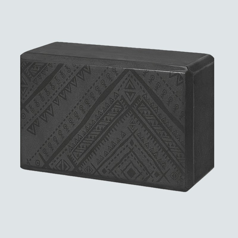 Black yoga block with geometric pattern on a light gray background